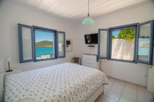 1 dormitorio con 1 cama y 2 ventanas en Cottage on the Sea en Ítaca