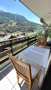 una mesa y sillas en un balcón con vistas en Sunny mountain view apartment in town by Jolidi, en Nendaz
