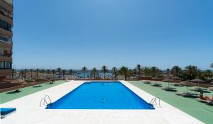 una piscina en un complejo con sillas y palmeras en Sur Suites Palmeras 491, en Fuengirola