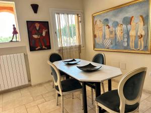 a dining room with a table and chairs and a painting at Monti Mannu Art in Abbiadori