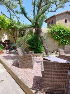 two wicker chairs and a tree in a yard at Le Logis des Remparts à l'intérieur de la Cité médiévale, Jardin privé, Parking inclus in Carcassonne