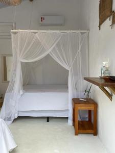 a bed with a canopy in a room with a table at Pousada Jardim da Praça in Caraíva