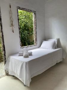 1 cama en una habitación con ventana en Pousada Jardim da Praça, en Caraíva