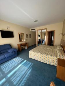 ein Hotelzimmer mit einem Bett und einem blauen Sofa in der Unterkunft Hotel Agrelo in Reboredo