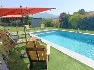 uma piscina com um guarda-sol e duas cadeiras e uma mesa em Bas de Villa neuf en Provence avec Piscine em Mallemoisson