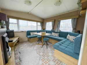 a living room with a blue couch and a table at Lovely 8 Berth Caravan With Decking At Eastgate Fantasy Island Park Ref 58004c in Skegness