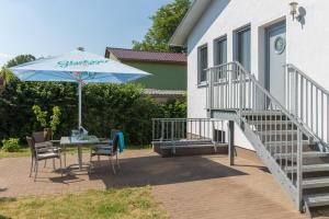 eine Terrasse mit einem Sonnenschirm, einem Tisch und Stühlen in der Unterkunft Villa-Meehr in Bantikow