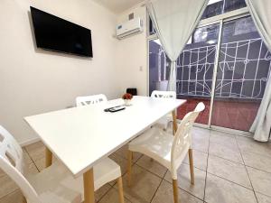 a white dining room with a white table and chairs at Volturino Aparts in Colón
