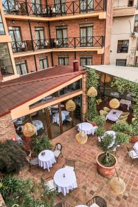 un patio extérieur avec des tables et des chaises en face d'un bâtiment dans l'établissement GINGER Hotel, à Tbilissi