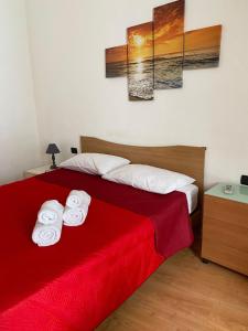 a bedroom with a red bed with two towels at Casa di Tony in Trapani