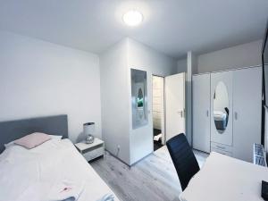 een witte slaapkamer met een bed en een stoel bij Restaurant Donau in Hannover