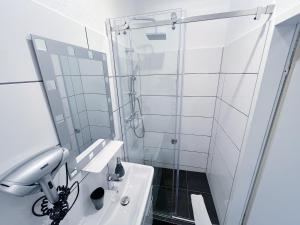 ein weißes Bad mit einer Dusche und einem Waschbecken in der Unterkunft Restaurant Donau in Hannover