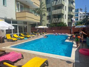 a large swimming pool with yellow chairs and umbrellas at Cleopatra Ada Apart in Alanya
