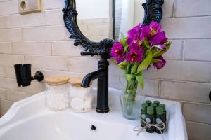 a sink with a vase of flowers and a mirror at hotelise I Tuff Apartment in Gyumri +54 photos