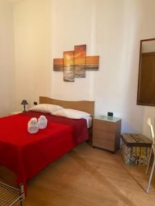 1 dormitorio con 1 cama roja y 2 toallas en Casa di Tony, en Trapani