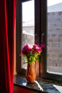 a vase filled with flowers sitting on a window sill at hotelise I Tuff Apartment in Gyumri