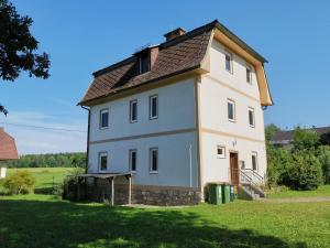 ein großes weißes Haus mit braunem Dach in der Unterkunft Bungalow & Apartments "Am Deber" Velden - Augsdorf in Velden am Wörthersee