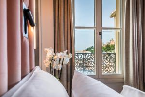 un jarrón de flores en una habitación con ventana en Palacio Gran Vía, a Royal Hideaway Hotel, en Granada