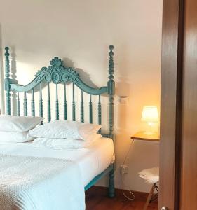 a bedroom with a bed with white sheets and a lamp at Quinta Amarela - B&B in Nazaré
