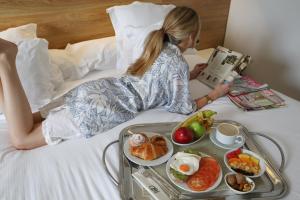 Una donna sdraiata su un letto con un vassoio di cibo di Hotel Monte Puertatierra a Cadice
