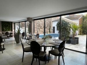 uma sala de jantar com mesa, cadeiras e janelas em Le Pavillon d'Enghien, Vichy Centre em Vichy