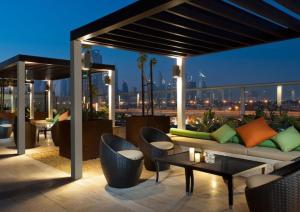 a rooftop patio with a couch and tables and chairs at Downtown Luxury - 5 star Hotel Facilities - 5 min walk to Dubai Mall in Dubai