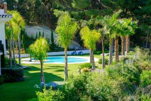 einen Garten mit Palmen und einem Pool in der Unterkunft Residencial SANNTONIO in La Herradura