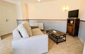 a living room with a white couch and a tv at Appartement privé Le Chardonnay, jardin, parking in Buchères