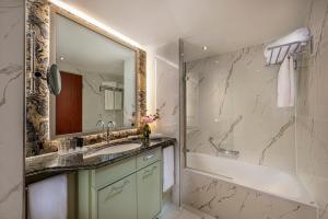 ein Badezimmer mit einem Waschbecken, einer Badewanne und einem Spiegel in der Unterkunft JW Marriott Hotel Berlin in Berlin