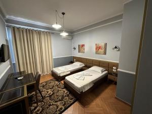 a hotel room with two beds and a desk at Edisem Hotel in Tirana