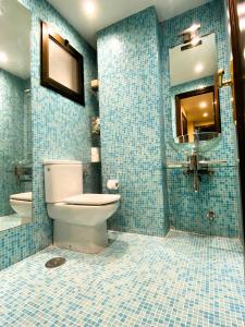 a blue tiled bathroom with a toilet and a mirror at Apartamento Playa Calzoa in Vigo