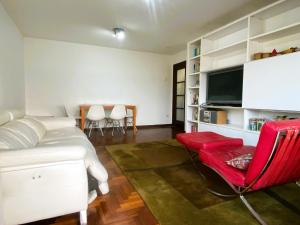 a bedroom with a bed and a tv and a red chair at Apartamento Playa Calzoa in Vigo