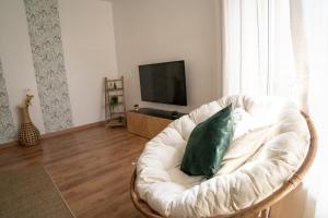 a white chair with a green pillow in a living room at Le Luma in Colmar