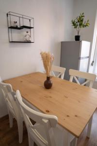 a wooden table with white chairs and a vase with flowers on it at Le Luma in Colmar