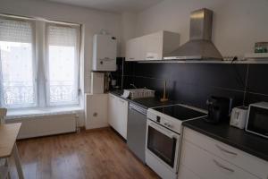 a kitchen with white cabinets and a stove top oven at Le Luma in Colmar