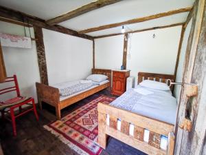 a bedroom with two beds in a room with a chair at Etno Selo Dodig in Drvar