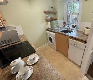 a kitchen with a sink and a washing machine at Ivy Cottage, in Lostwithiel