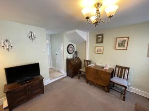 a living room with a television and a table with chairs at Ivy Cottage, in Lostwithiel
