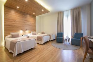 a hotel room with three beds and two chairs at Hotel Monte Puertatierra in Cádiz