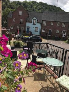 een patio met een tafel, stoelen en bloemen bij Salthouse Cottage in Ironbridge in Telford