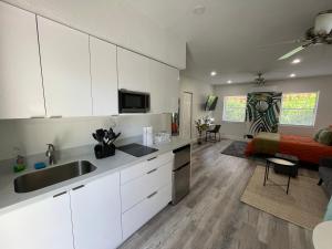 a kitchen with white cabinets and a living room with a bed at Casa Habana Studios in Miami