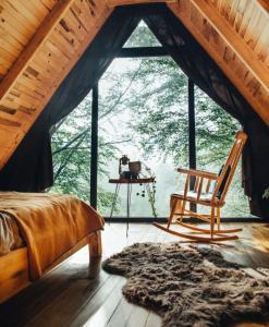 een slaapkamer met een bed en een stoel voor een raam bij bungalov in Rize