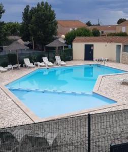 duży niebieski basen z krzesłami i stołami w obiekcie Appartement T2, terrasse, piscine, clim, proche plage w mieście Marseillan