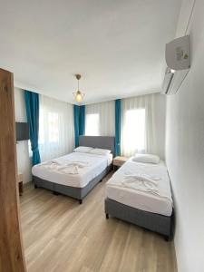 two beds in a room with blue curtains at Gülhan City Otel in Datca