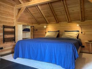 um quarto com uma cama azul num chalé de madeira em The Miller's Lodge B&B 