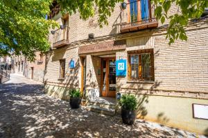 un bâtiment avec deux plantes en pot devant lui dans l'établissement YIT Puerta Bisagra, à Tolède