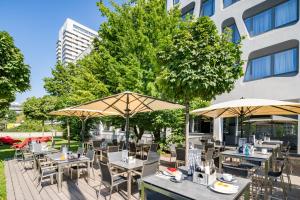 eine Außenterrasse mit Tischen, Stühlen und Sonnenschirmen in der Unterkunft Best Western Hotel Arabellapark Muenchen in München