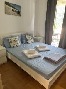 a large bed with two towels on top of it at Lavender Bay Apartment in Donji Morinj