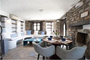 een woonkamer met een stenen muur en een tafel en stoelen bij Villa Aspro Paros 1 in Drios