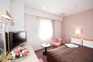 a hotel room with a bed and a flat screen tv at Hotel Unisite Sendai in Sendai